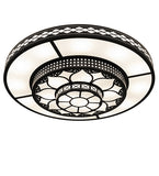 A round ceiling light fixture with a black metal frame and white frosted glass panels, featuring intricate geometric and floral cutout patterns.