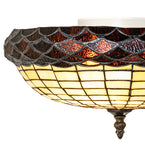 A close-up of a semi-flush mount wall light fixture with a scalloped mosaic shade. The top band features textured amber and dark brown glass scales, while the lower bowl has a warm yellow grid pattern.